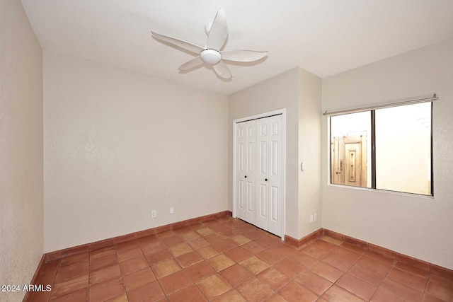 unfurnished bedroom featuring light tile patterned floors, a closet, a ceiling fan, and baseboards