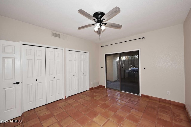 unfurnished bedroom featuring a ceiling fan, tile patterned flooring, visible vents, and multiple closets