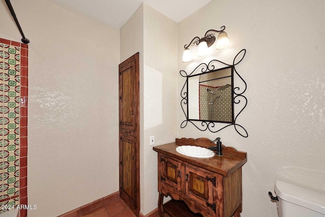 bathroom featuring toilet, vanity, baseboards, tile patterned floors, and walk in shower