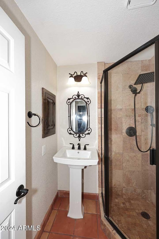 bathroom with baseboards, a shower stall, a textured ceiling, and tile patterned floors