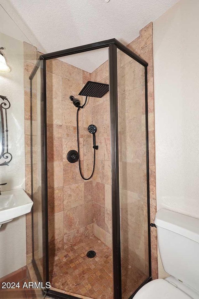 bathroom featuring a textured ceiling, a stall shower, and toilet