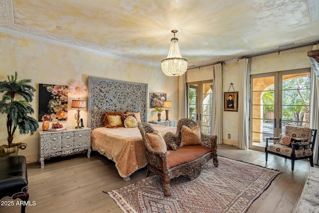 bedroom featuring an inviting chandelier, wood-type flooring, french doors, and access to exterior