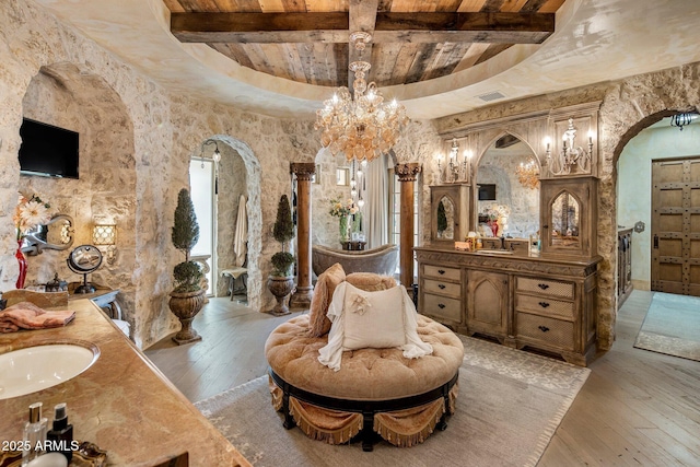 bathroom with a notable chandelier, hardwood / wood-style floors, vanity, and beam ceiling