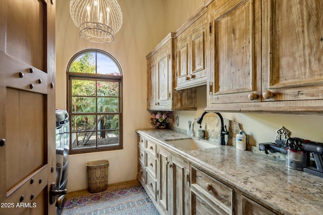 interior space featuring sink, an inviting chandelier, light tile patterned floors, light stone countertops, and pendant lighting