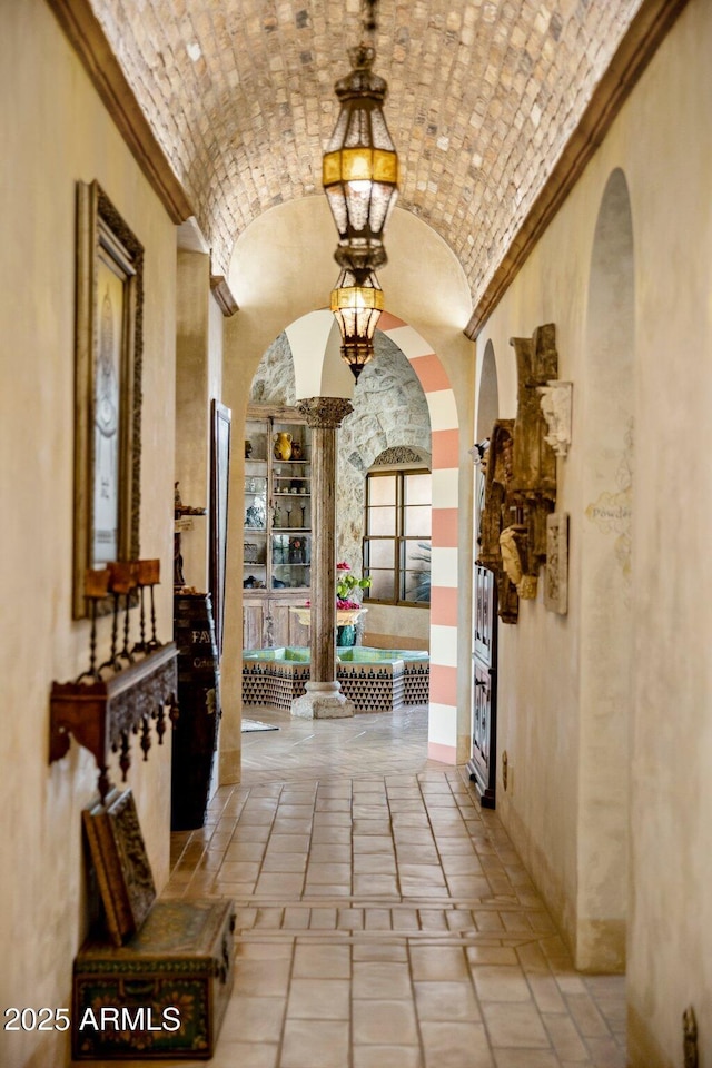 hall with lofted ceiling and brick ceiling