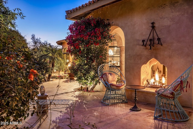 patio terrace at dusk featuring exterior fireplace