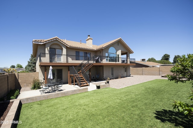 rear view of property with a chimney, a lawn, a fenced backyard, a patio, and stairs