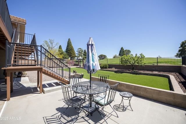 view of patio with outdoor dining area, fence, and stairway