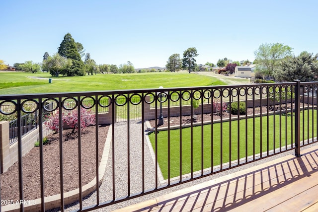 view of gate with golf course view, fence, and a yard