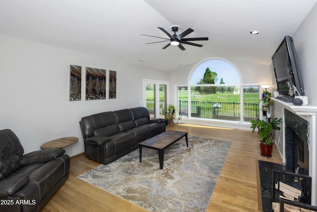 living room with a ceiling fan, a healthy amount of sunlight, lofted ceiling, and a high end fireplace