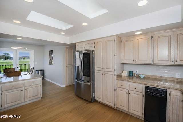 kitchen featuring light brown cabinets, refrigerator with glass door, a skylight, and light wood-style floors