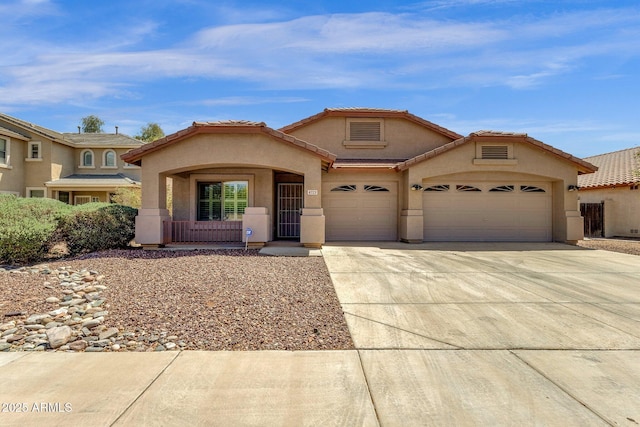 mediterranean / spanish home featuring an attached garage, driveway, a tile roof, and stucco siding