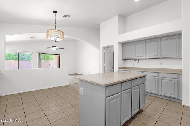 kitchen with a kitchen island, visible vents, arched walkways, gray cabinetry, and light tile patterned flooring