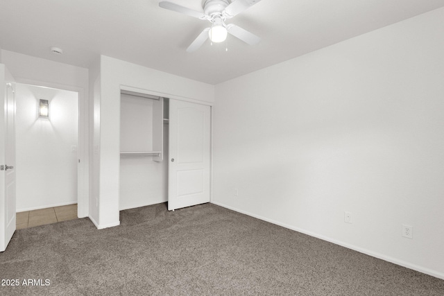 unfurnished bedroom with a closet, carpet flooring, baseboards, and ceiling fan