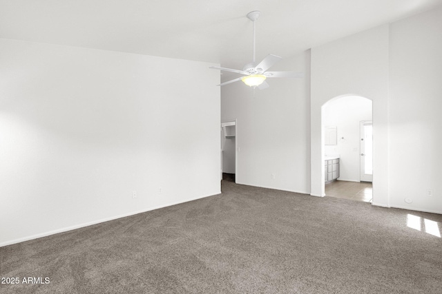 spare room with ceiling fan, arched walkways, baseboards, high vaulted ceiling, and carpet flooring