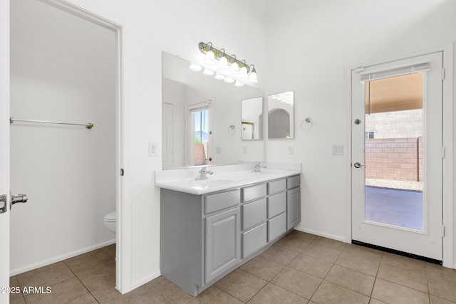 bathroom with plenty of natural light, double vanity, tile patterned flooring, and toilet