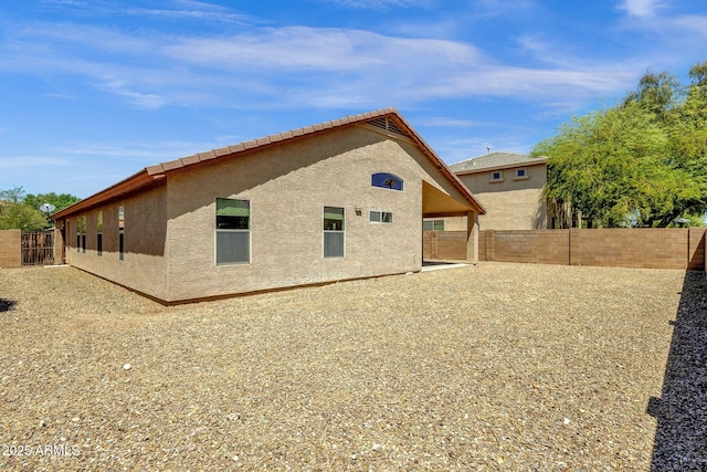 rear view of house with a fenced backyard and stucco siding