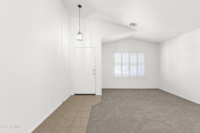 spare room featuring visible vents, baseboards, tile patterned floors, and vaulted ceiling