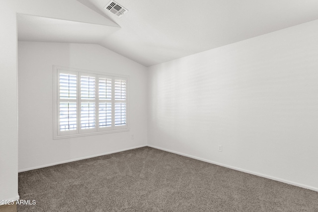 unfurnished room with baseboards, vaulted ceiling, dark colored carpet, and visible vents