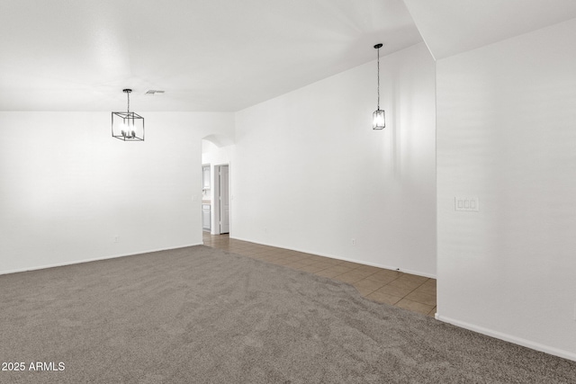 carpeted empty room featuring tile patterned flooring, visible vents, arched walkways, baseboards, and vaulted ceiling