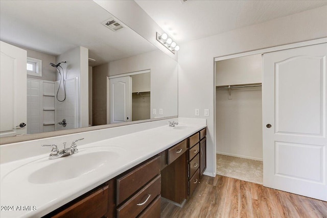 bathroom featuring vanity, a shower, and wood-type flooring