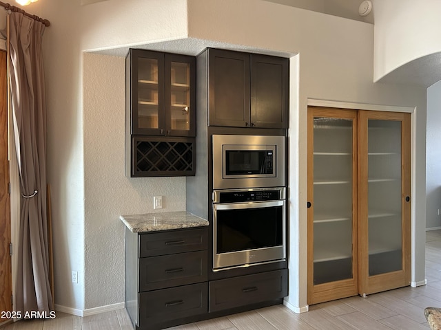 694 W Beechnut Dr, Chandler, AZ 85248 - kitchen with stainless steel appliances, light stone counters, glass insert cabinets, and a textured wall