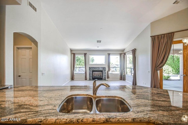 694 W Beechnut Dr, Chandler, AZ 85248 - kitchen with stone counters, a glass covered fireplace, open floor plan, and arched walkways