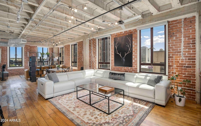 living room with track lighting, light wood-type flooring, ceiling fan, and brick wall