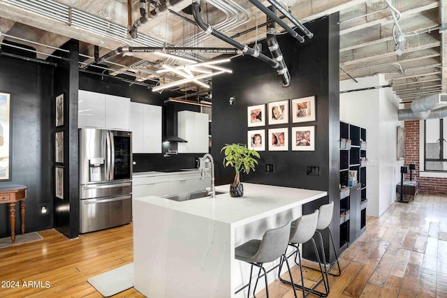 kitchen featuring white cabinets, light wood-type flooring, stainless steel fridge, and sink