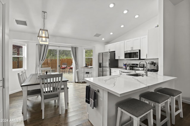 kitchen featuring vaulted ceiling, decorative light fixtures, white cabinetry, kitchen peninsula, and stainless steel appliances