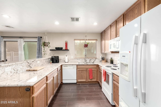 kitchen featuring a peninsula, white appliances, a sink, and visible vents