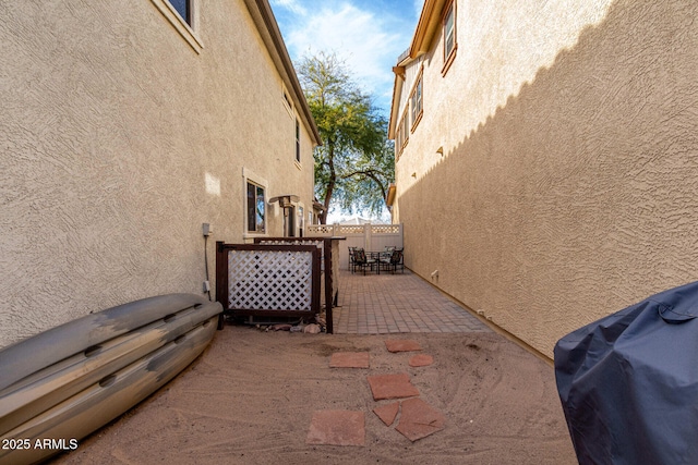 view of property exterior with outdoor dining area, a patio, fence, and stucco siding