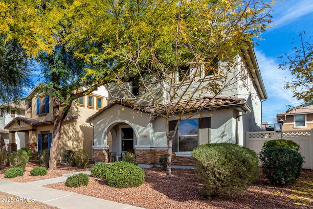 view of front of home featuring a tile roof, fence, and stucco siding