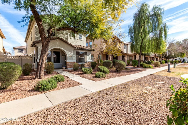 view of front of house with a tile roof, fence, and stucco siding