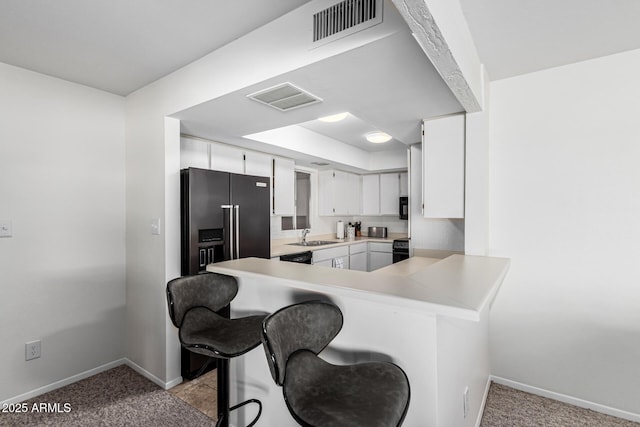 kitchen with sink, a breakfast bar area, white cabinets, high end refrigerator, and kitchen peninsula