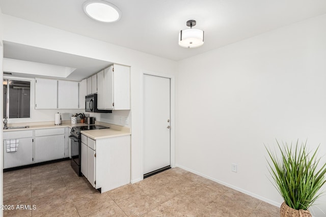 kitchen with sink, light tile patterned floors, white cabinets, and black appliances