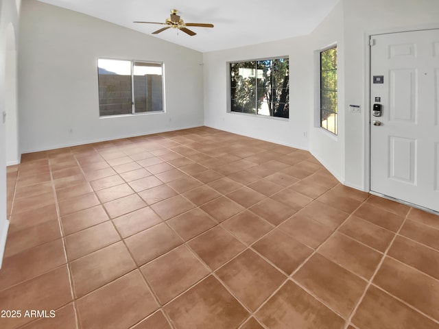 tiled foyer entrance with ceiling fan and lofted ceiling