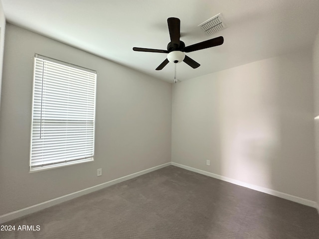 spare room featuring dark carpet and ceiling fan