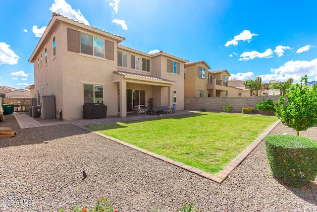 rear view of house with a patio, stucco siding, a fenced backyard, and a lawn