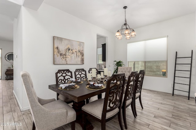 dining space with light wood-type flooring and an inviting chandelier