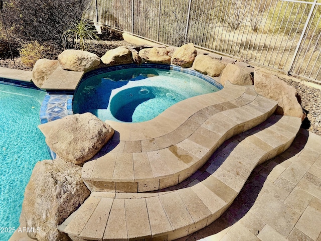 pool with an in ground hot tub and fence