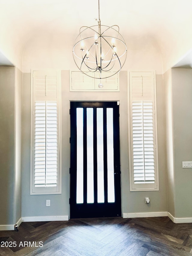 foyer entrance featuring a chandelier and baseboards