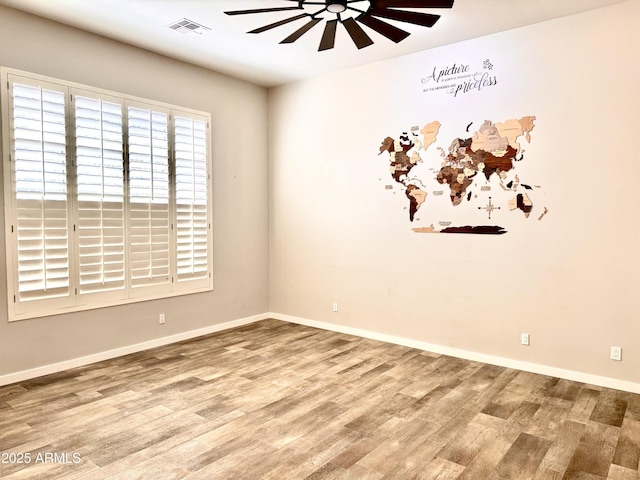 spare room featuring visible vents, ceiling fan, baseboards, and wood finished floors