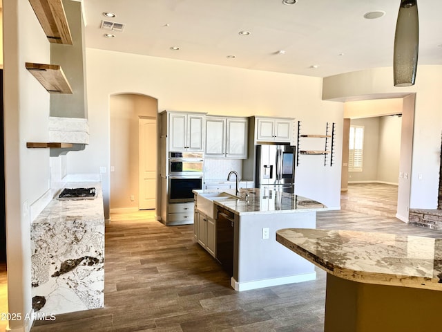 kitchen with visible vents, dark wood finished floors, a kitchen island with sink, stainless steel appliances, and a sink