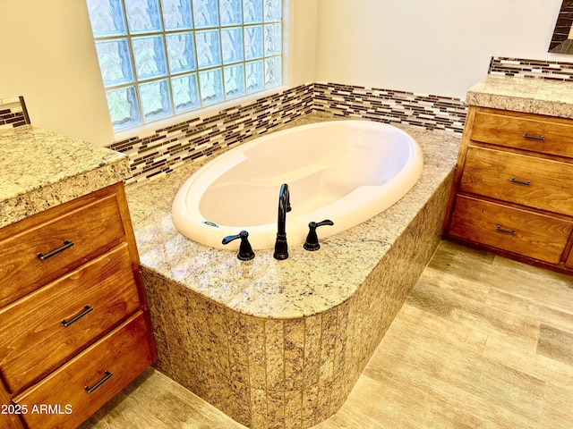 full bath with vanity, decorative backsplash, and a bath