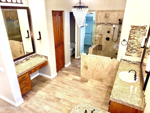 bathroom with tiled shower, vanity, toilet, and wood finished floors