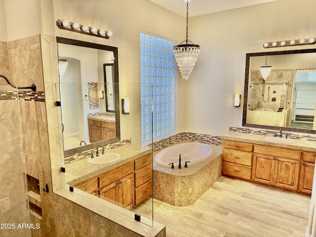 full bathroom with a bath, walk in shower, a sink, and wood finished floors