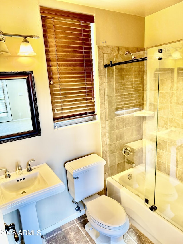 bathroom featuring tile patterned flooring, combined bath / shower with glass door, a sink, and toilet