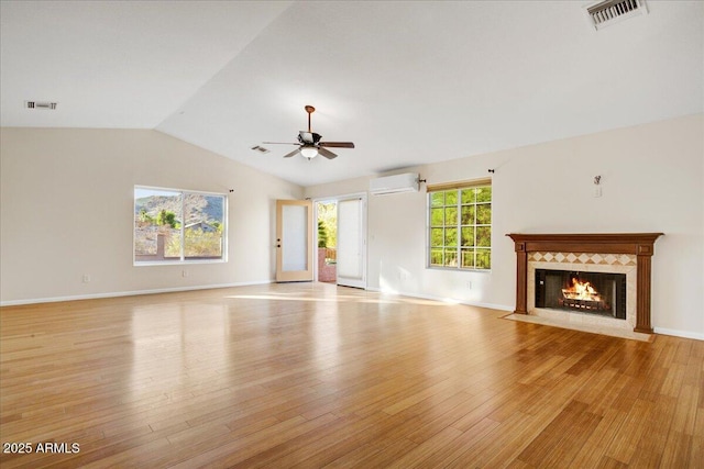 unfurnished living room featuring light wood finished floors, ceiling fan, visible vents, and a wall unit AC