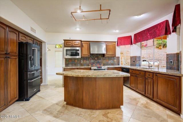 kitchen featuring wall chimney range hood, a sink, stainless steel appliances, backsplash, and visible vents